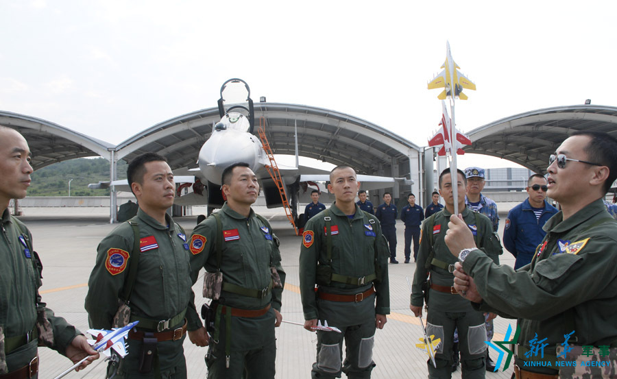 ↑艦載航空兵某部司令員戴明盟向飛行員演示空中飛行注意事項。